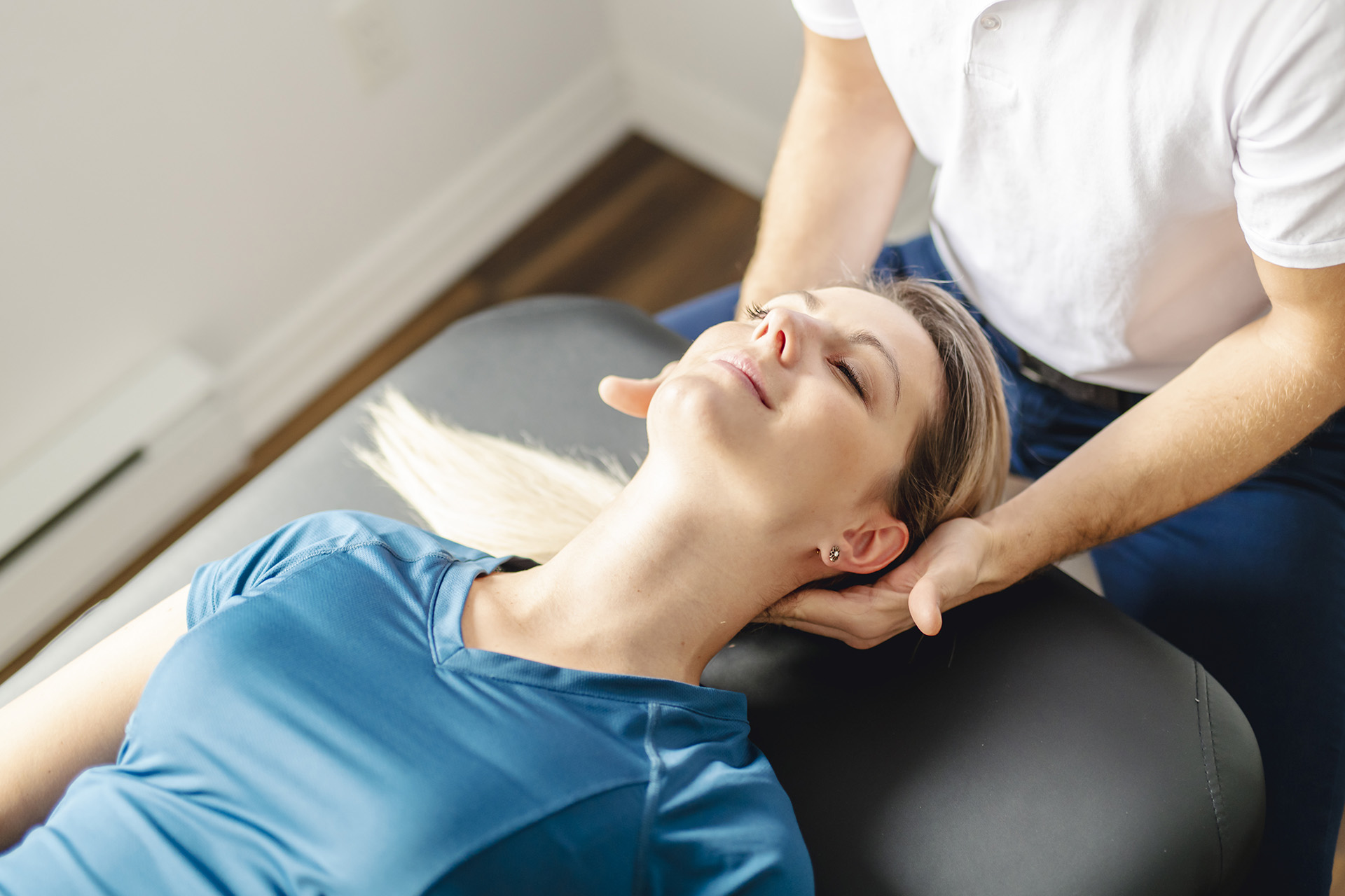 Woman laying on back while a male physical therapist adjusts her neck